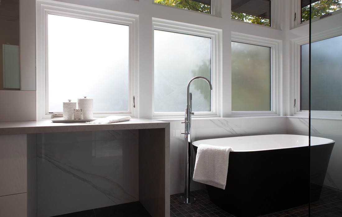 Freestanding tub and vanity view with film windows in Toronto luxury bathroom