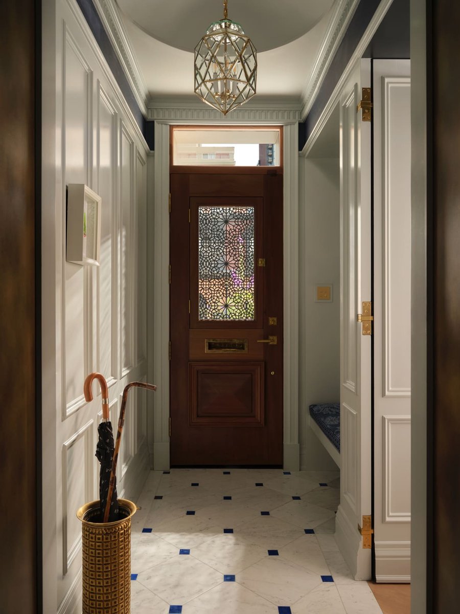 Bright Toronto entryway with wood front door, patterned marble floor, brass lantern, and built-in bench