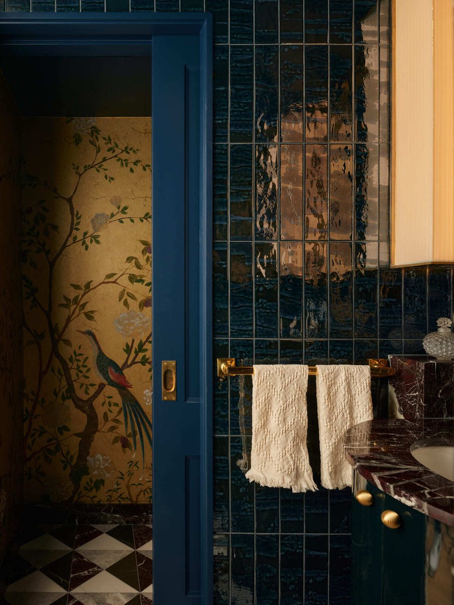 Detailed bathroom view with blue tile walls, brass towel bar, patterned floor tile, and floral wallpaper in Toronto