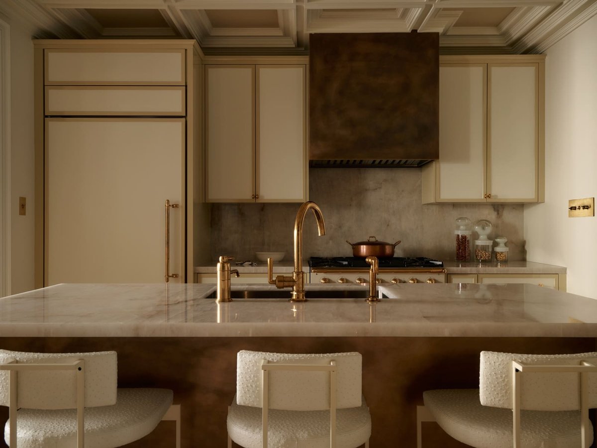Elegant Toronto kitchen featuring marble island, brass fixtures, custom cabinets, and a statement range hood