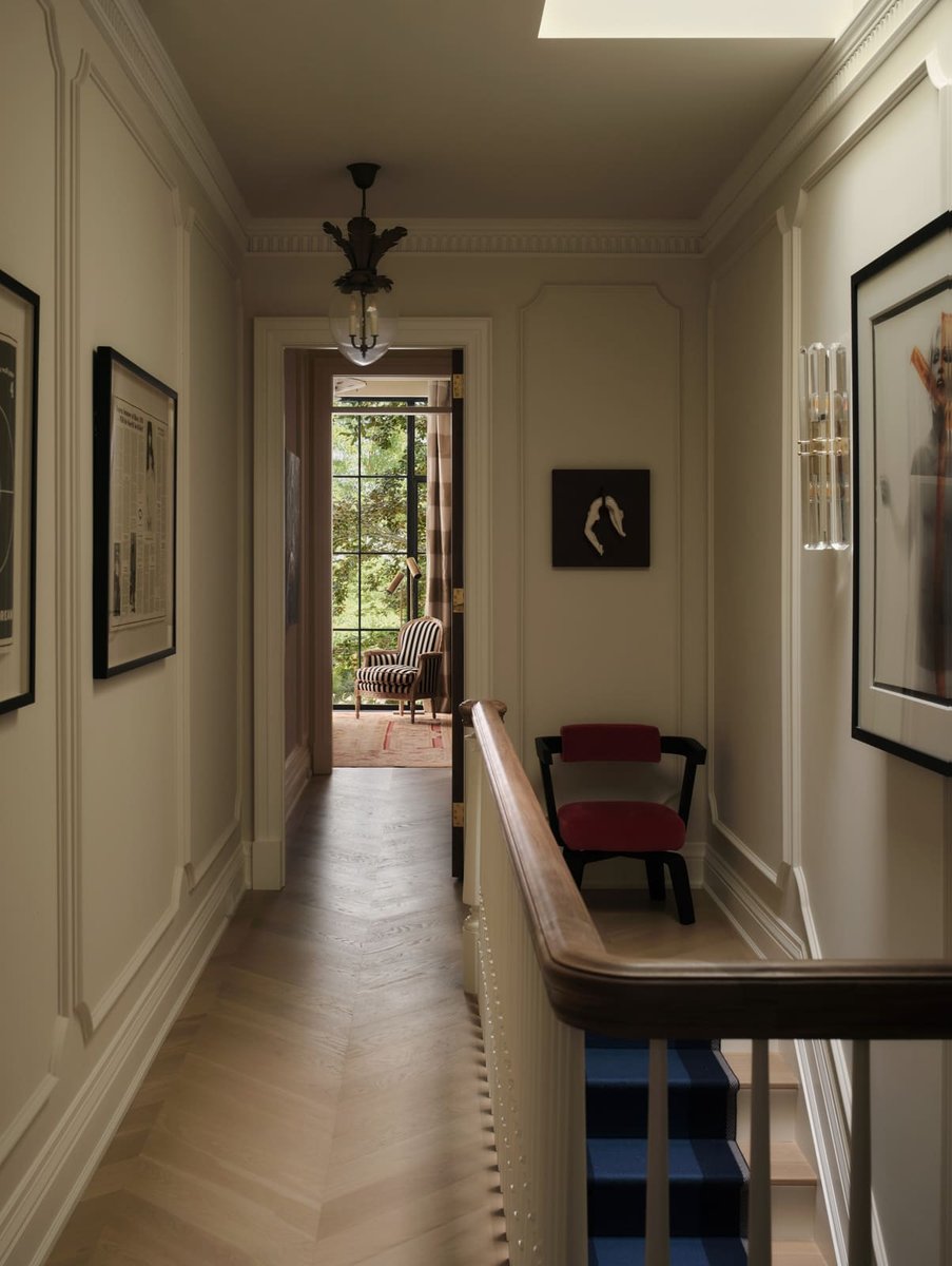 Hallway with staircase railing, framed artwork, and natural light at the end, located in Toronto