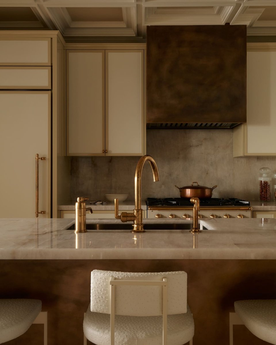 Luxury kitchen island with marble counters, brass faucet, custom cabinetry, and range hood in a Toronto home