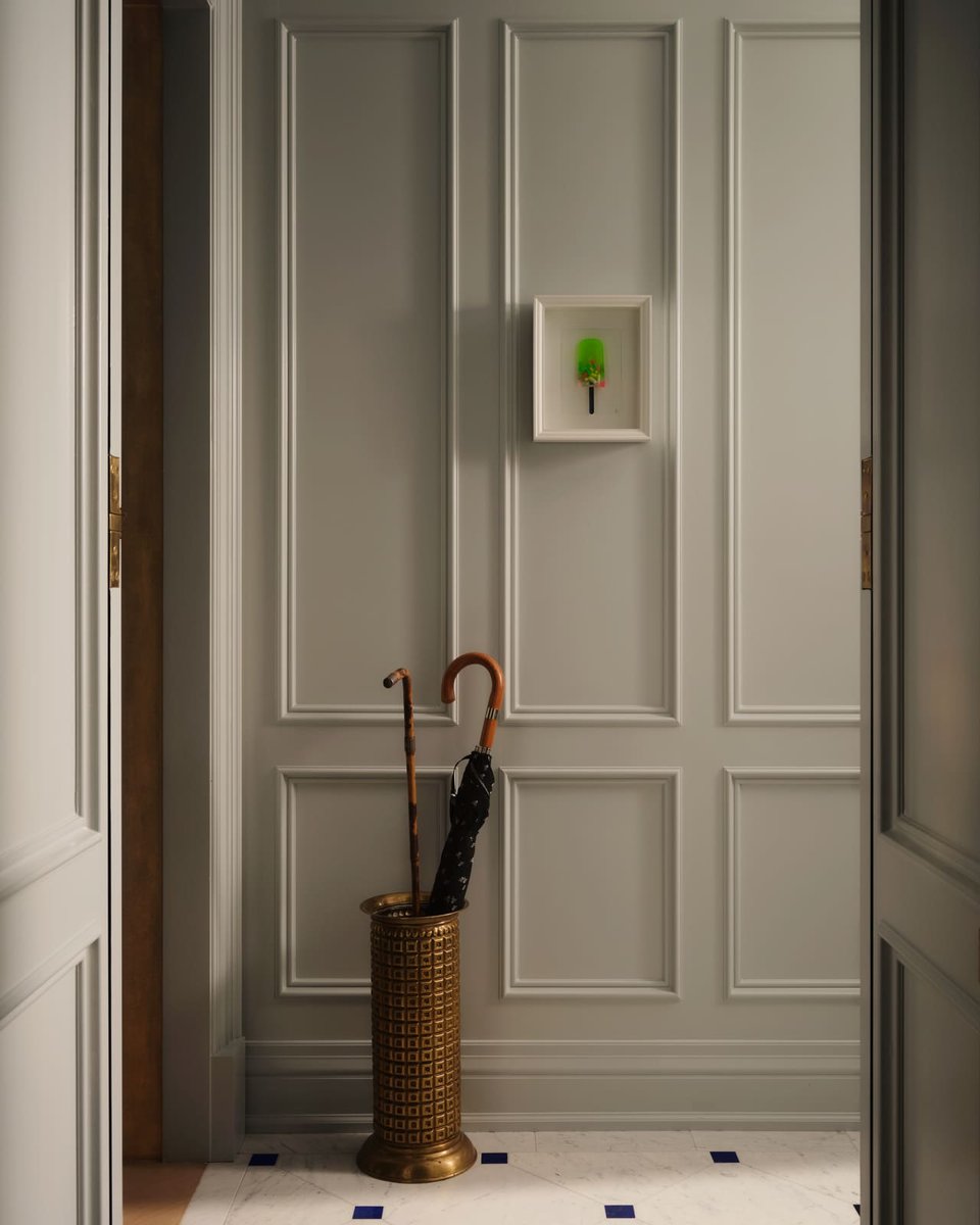 Paneled Toronto hallway wall with framed art and umbrella stand on marble tile flooring