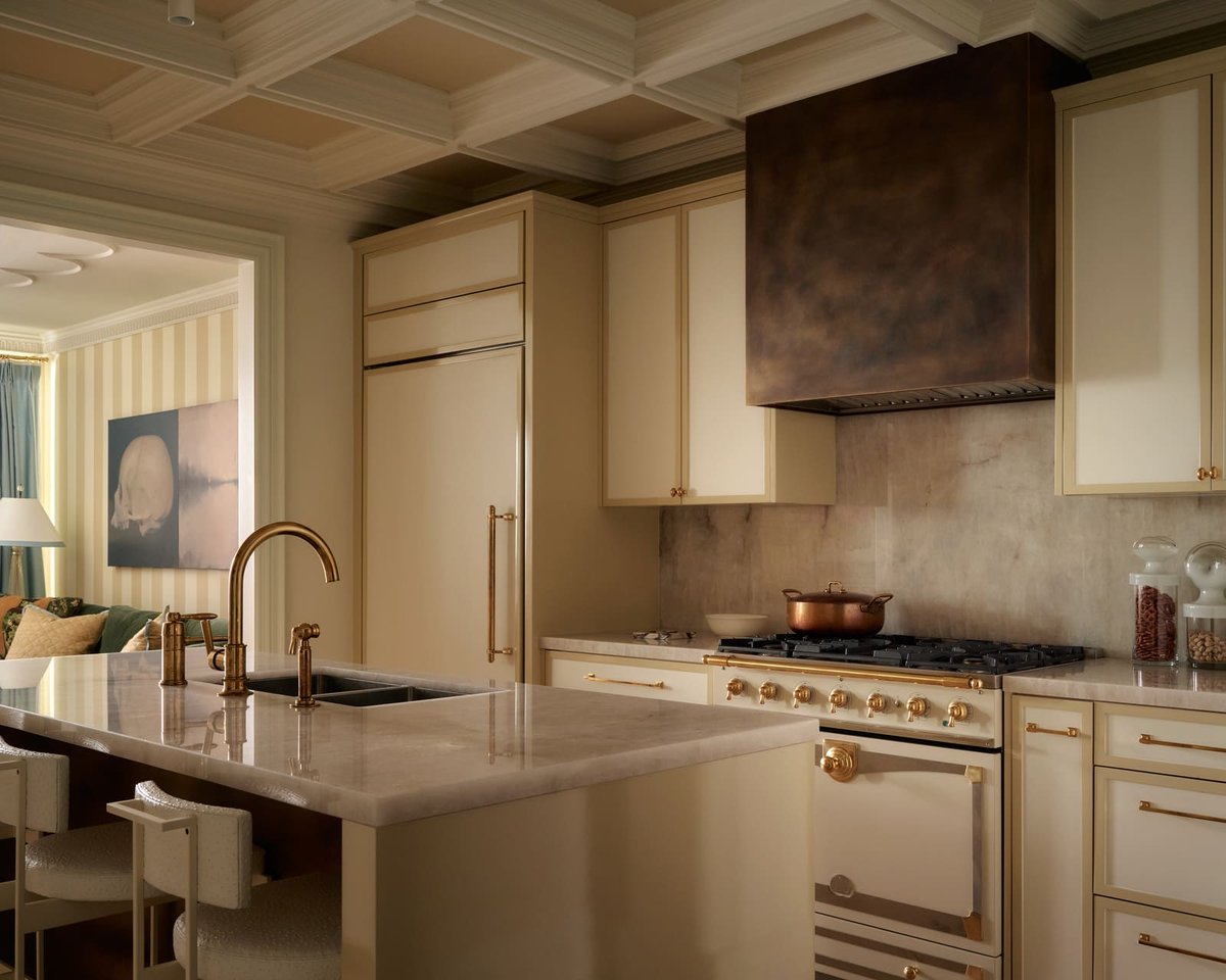 Toronto kitchen featuring marble island, cream cabinetry, brass hardware, coffered ceiling, and professional range in a refined space