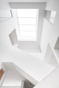 Artistic angular edges mixed with rounded, organic shapes looking up at staircase skylight