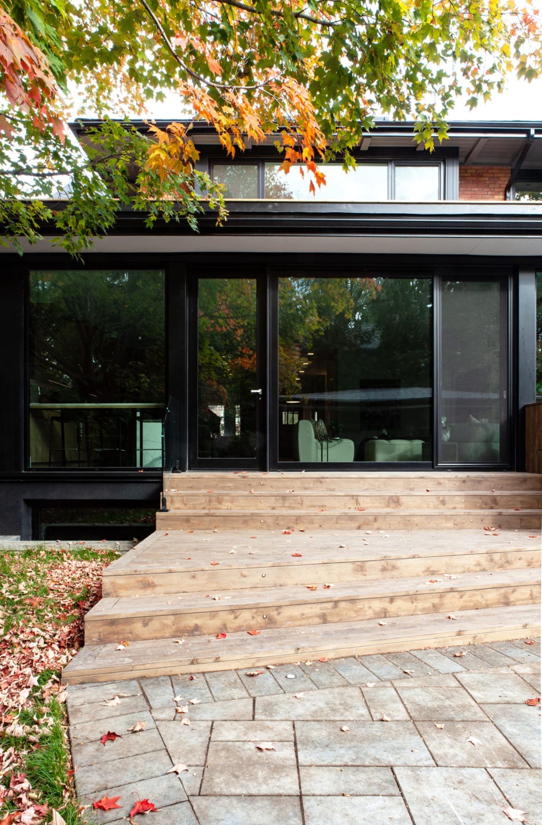 Back exterior view of renovated luxury home in Toronto with steps leading to glass door