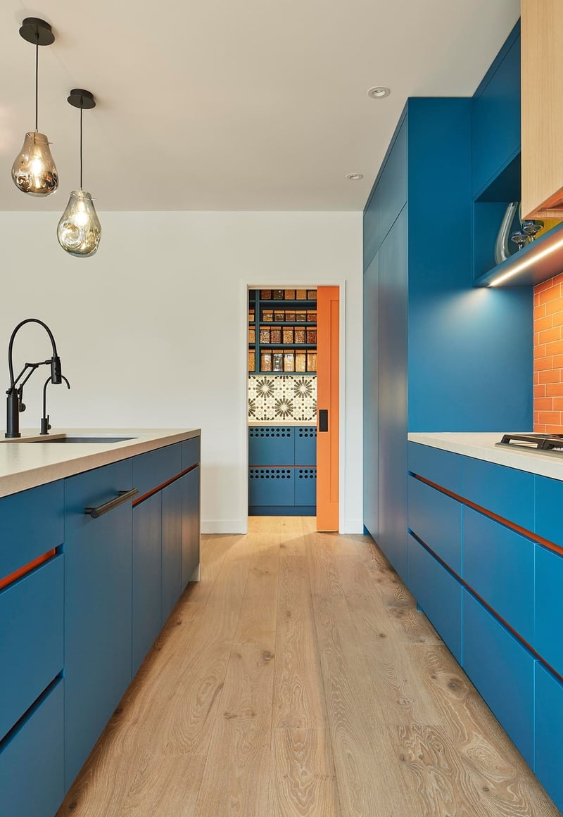 Blue flat panel cabinets with orange subway tile backsplash in Toronto home renovation by SevernWoods