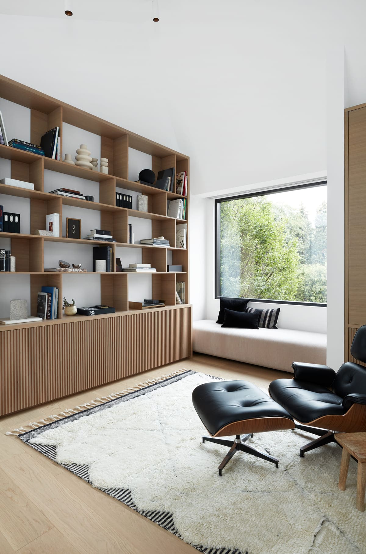 Chair and rug in front of custom-built bookshelf in office of Toronto custom home by SevernWoods