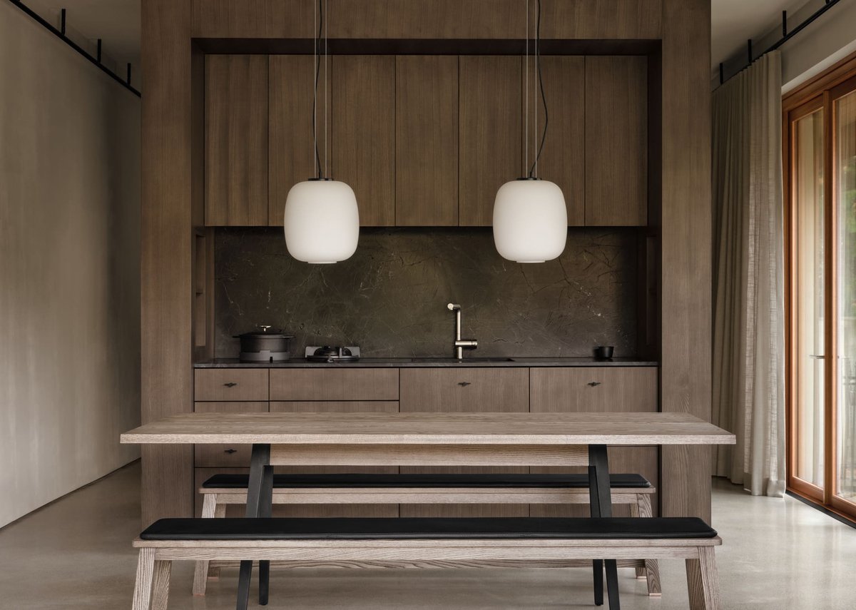 Toronto dining space with wood table and benches, pendant lights, and built-in kitchen framed by clean lines and warm natural materials