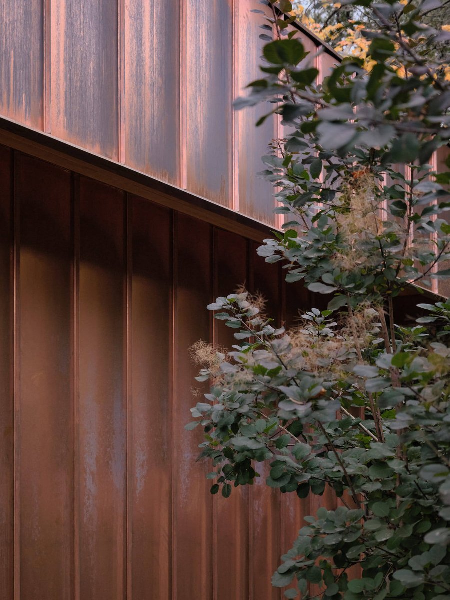 Toronto home exterior detail with patina copper siding and surrounding greenery, highlighting modern materials and landscaping