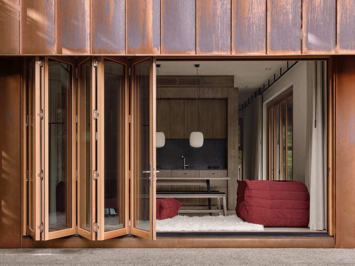 Toronto home with folding glass doors opening to interior seating area, wood finishes, and modern kitchen visible through wide opening