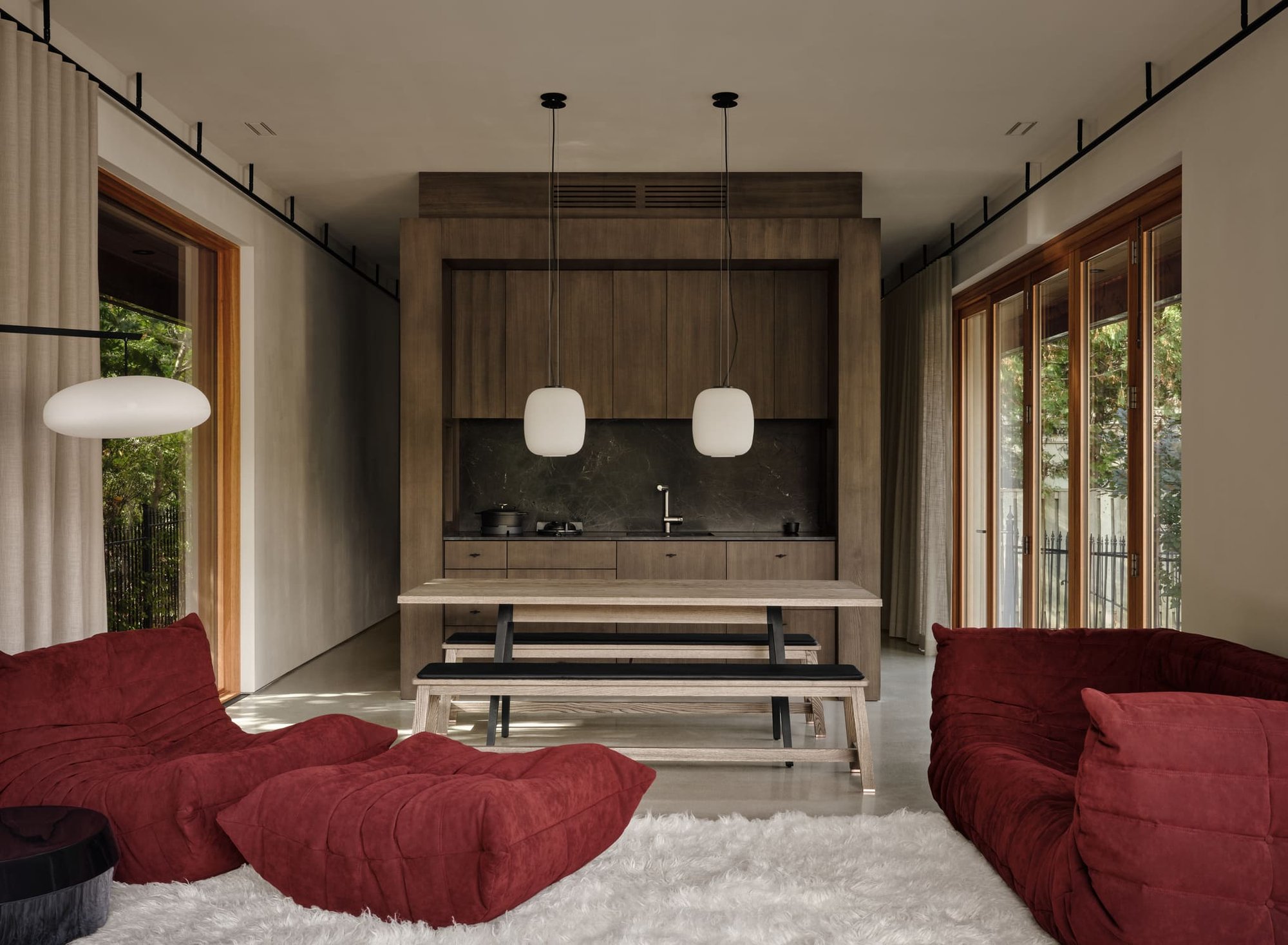 Toronto modern interior with wood kitchen, pendant lighting, long dining table, and red lounge seating in a minimalist open-concept space Toronto modern interior with wood kitchen, pendant lighting, long dining table, and red lounge seating in a minimalist open-concept space