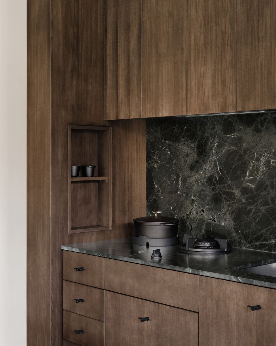Toronto modern kitchen detail with wood cabinetry, dark stone backsplash, and minimalist cooktop in a sleek, contemporary design