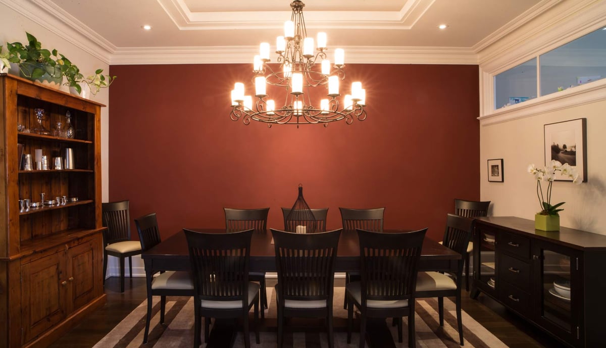 Dining room with chandelier above table and dark red accent wall in Leaside, Toronto