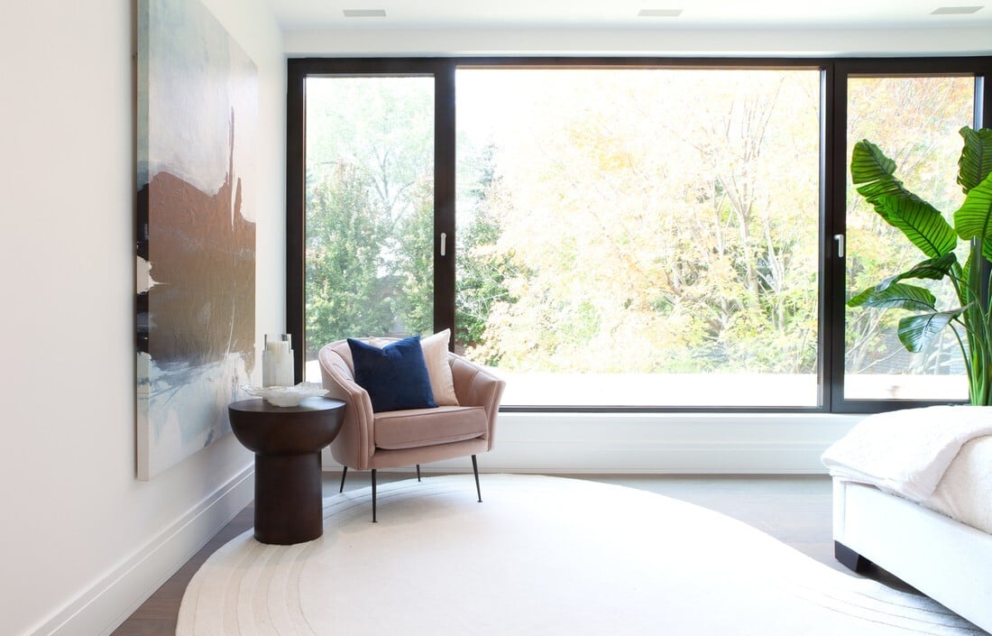 expansive-window-behind-chair-and-side-table-in-bedroom-in-toronto-custom-home