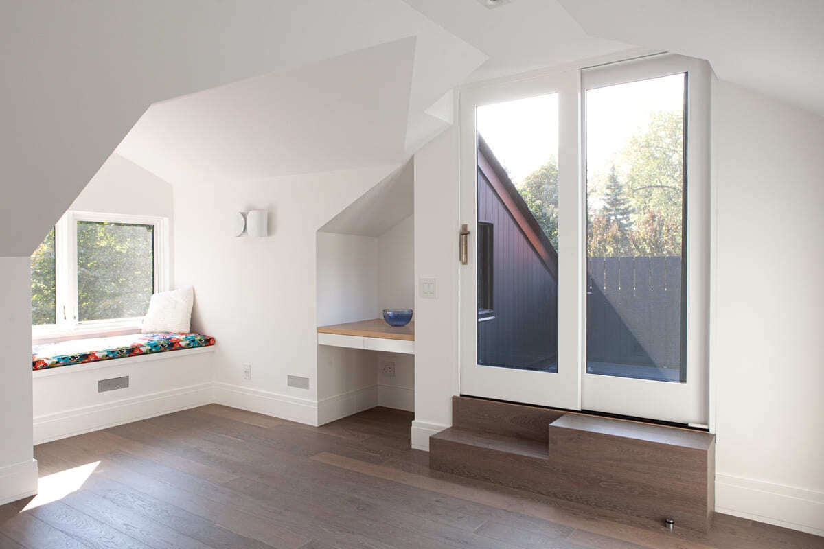 second-storey-room-in-toronto-home-renovation-with-seating-by-window-and-glass-door-to-balcony