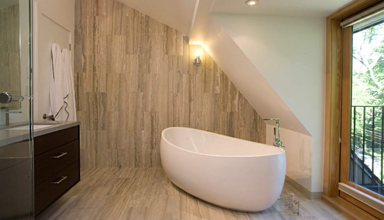Freestanding bathtub under sloped ceiling in modern Toronto bathroom with wood accents