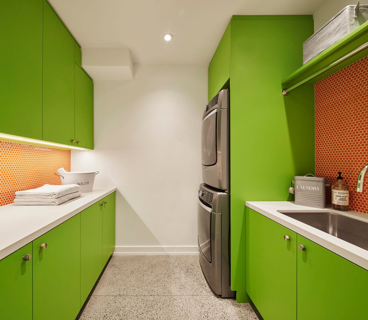 Laundry room in basement with green cabinets and orange tiled backsplash 
