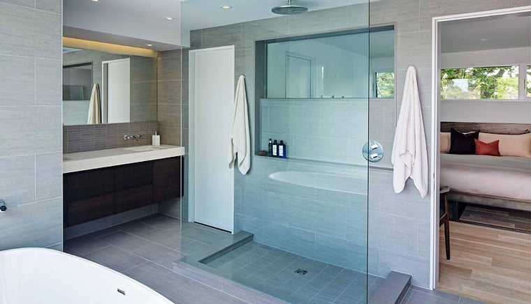 Modern bathroom with glass shower, soaking tub, and gray tile located in Leslieville