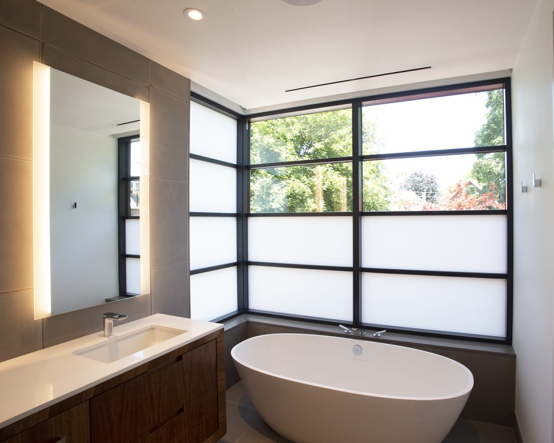 Modern Bathroom With Half Frosted Windows With Black Trim. Build-In Vanity and Freestanding Tub Featured