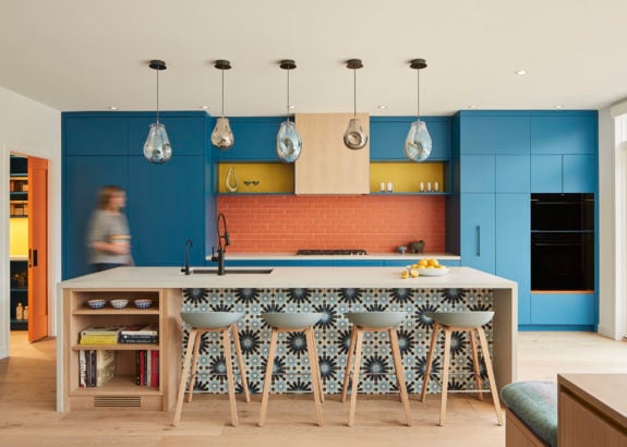 Toronto kitchen with blue cabinetry, patterned tile island, wood stools, and pendant lighting over a modern open layout