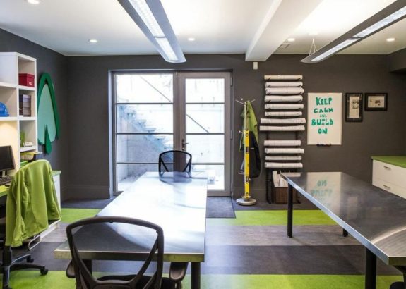 Toronto office space with modern desks, glass doors, gray walls, green accents, and organized workstations with wall-mounted racks