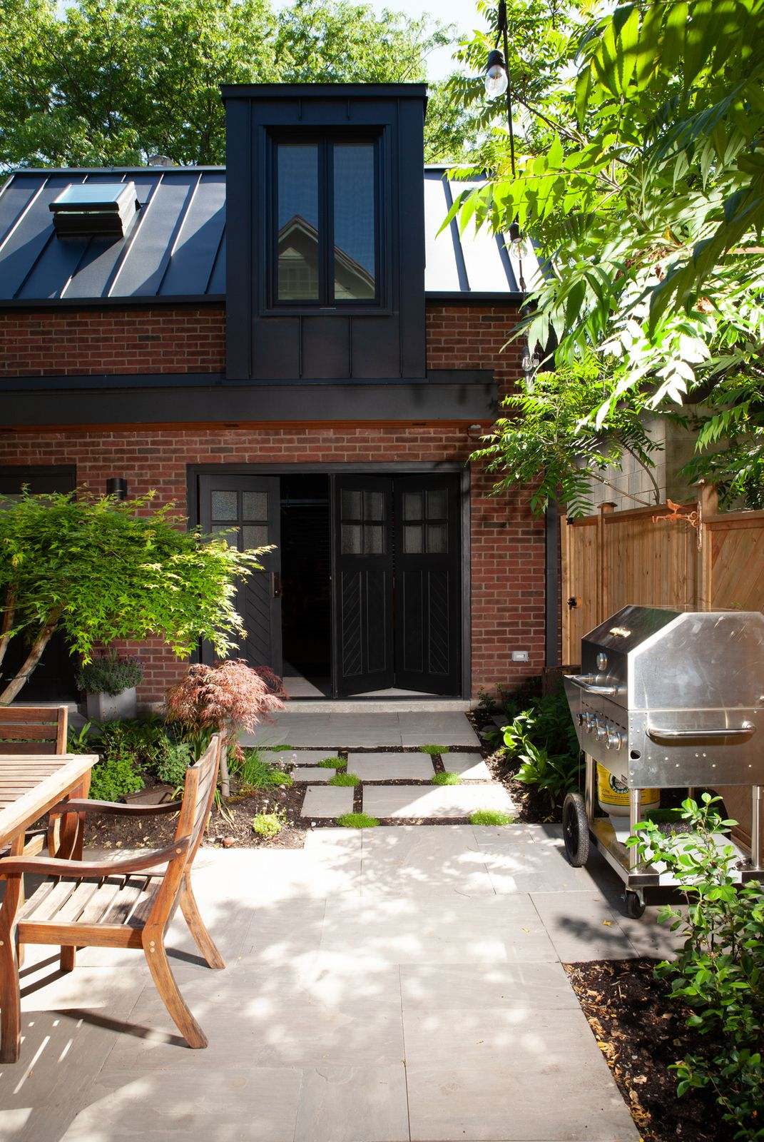 Traditional brick laneway house in Danforth on sunny day with bi-fold black doors