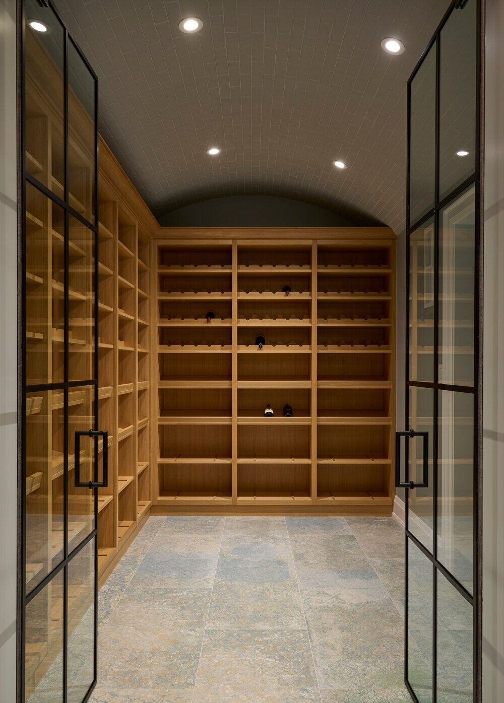 Arched wine cellar with oak shelving and tile flooring by Cesario and Co in Toronto home by SevernWoods, photographed by Alex Lukey Photography