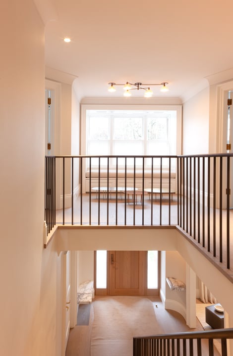 Top of staircase in front of foyer with railing in front of window by SevernWoods