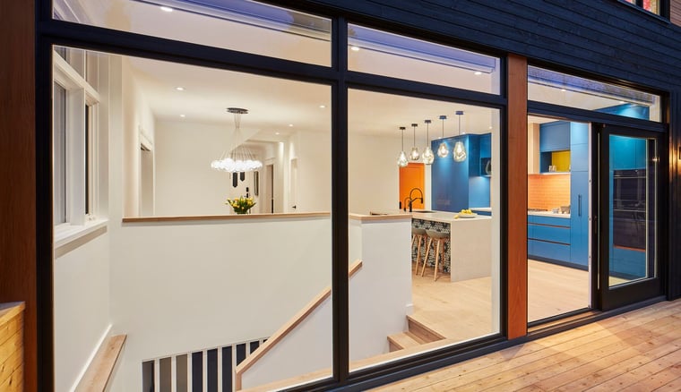 Exterior view of floor-to-ceiling windows looking inside custom colourful kitchen