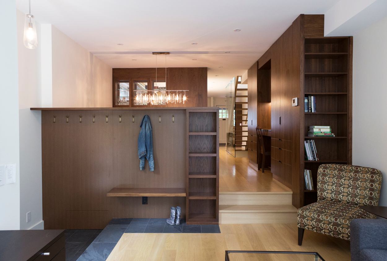 Built-In Wood Storage With Row of Hooks and Shelves Near Entryway of Home.