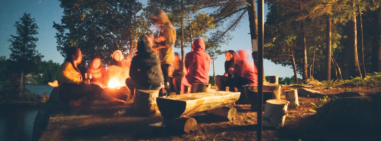 group of people camping in ontario around fire on log benches (2)