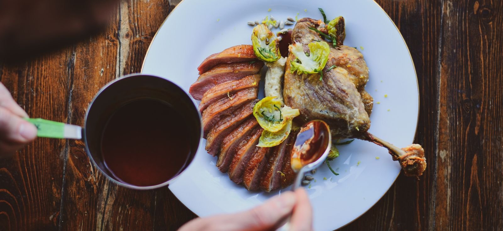 perfectly seared duck being drizzled with sauce in fancy restaurant in lytton park