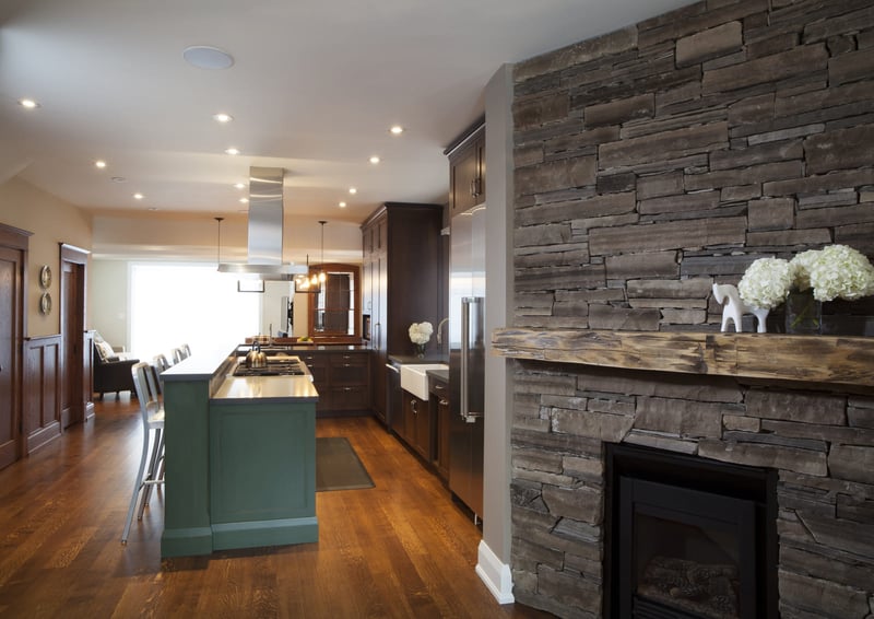 Stone fireplace detailing with view of kitchen