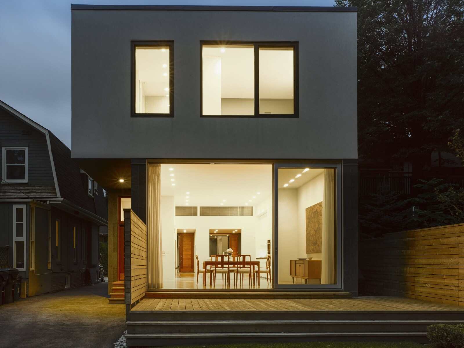 Custom home exterior at night with large windows looking into home