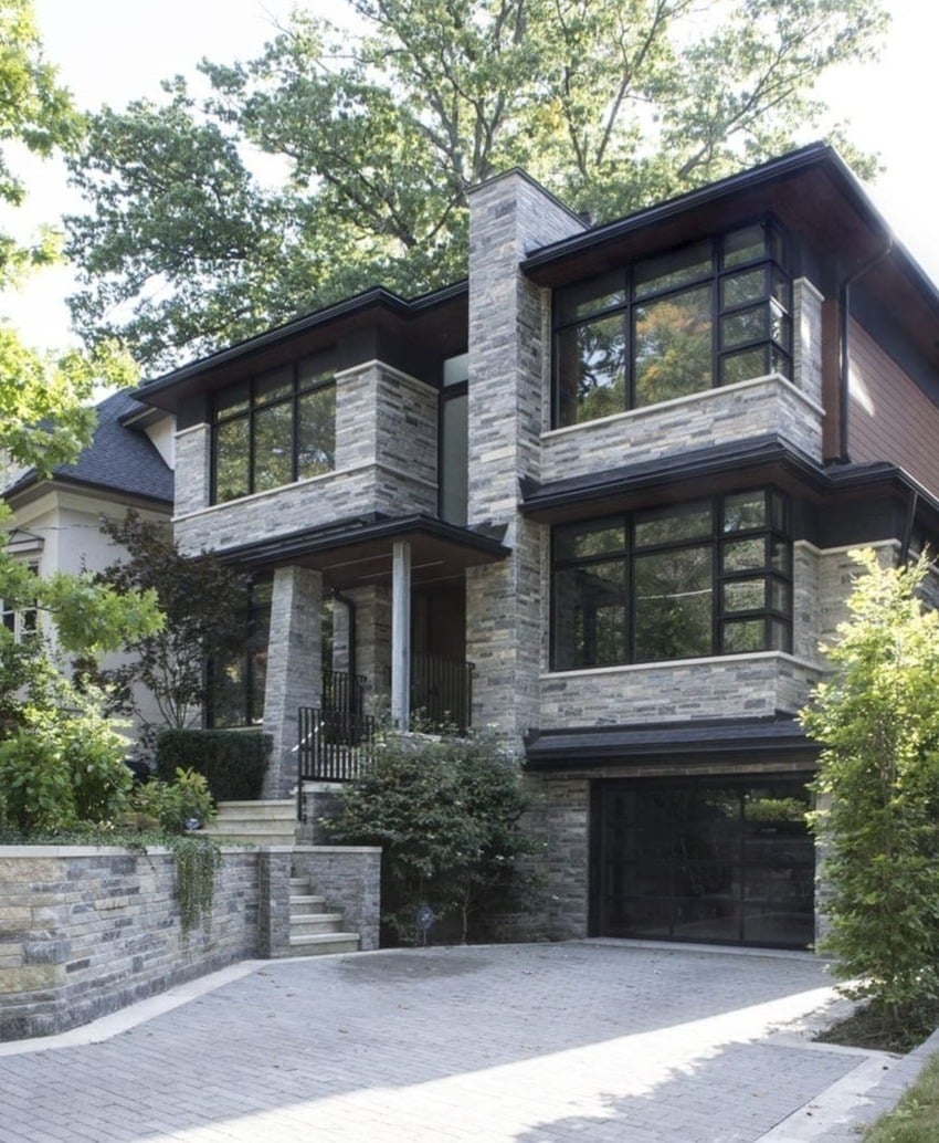 Modern stone and glass home in the Greater Toronto Area featuring clean lines, expansive windows, and a sleek driveway leading to a built-in garage
