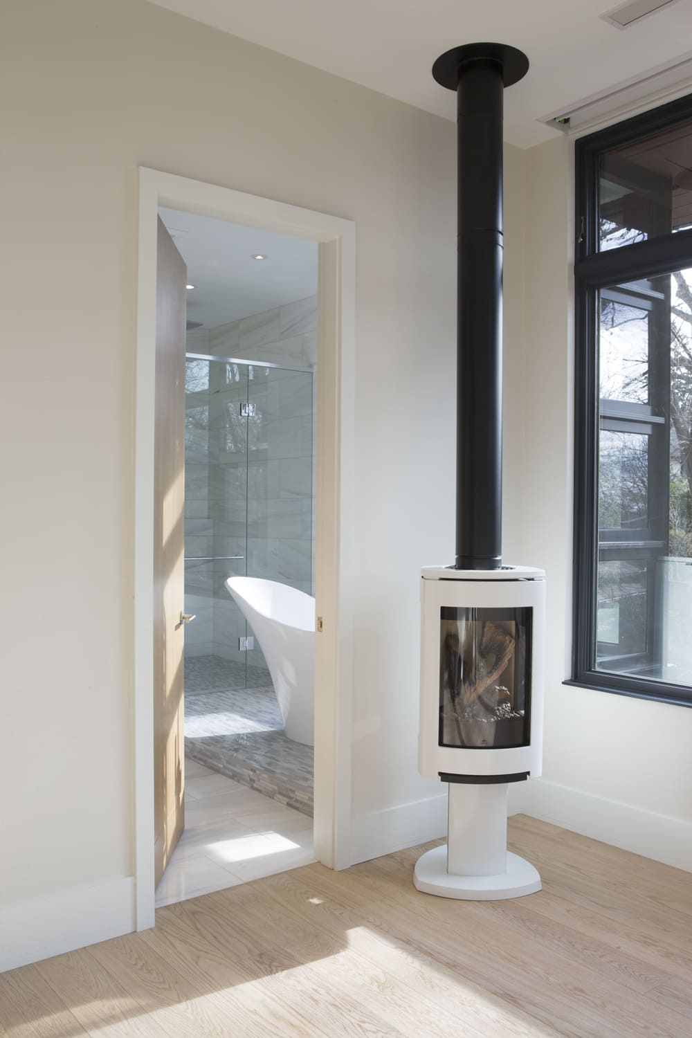 white-oak-flooring-and-door-open-to-bathroom-with-natural-light