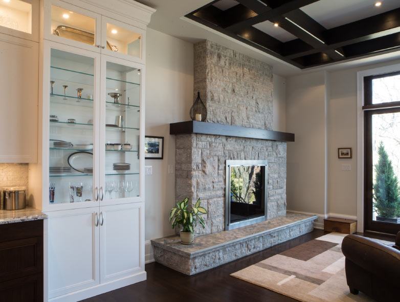 Stone fireplace in luxury custom family room with built-in bookshelf