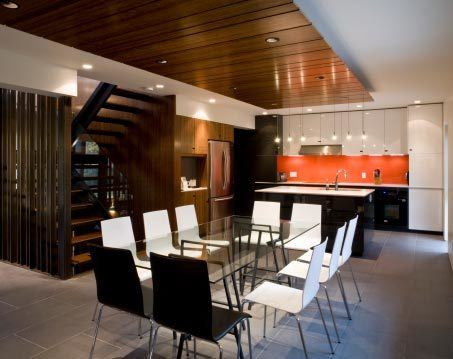 Open-concept dining area and view of kitchen with glass dining table and white chairs