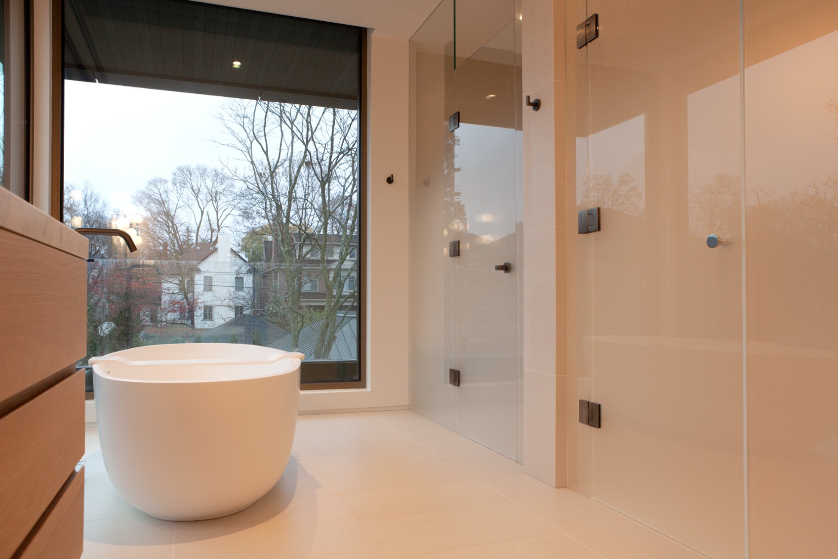 Luxury bathroom with white freestanding tub in front of frosted window by SevernWoods