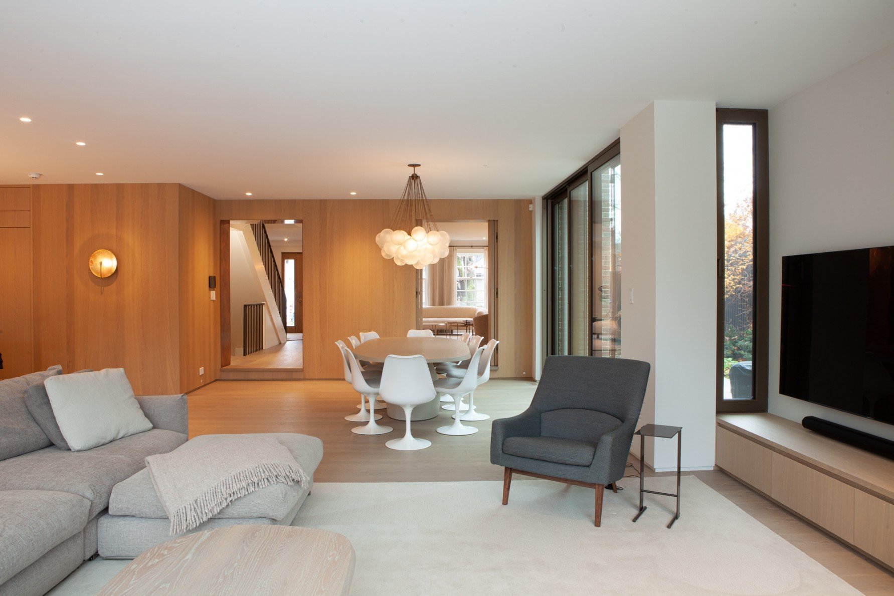 Open-concept dining and living room area with light fixture above dining table in Toronto addition and renovation