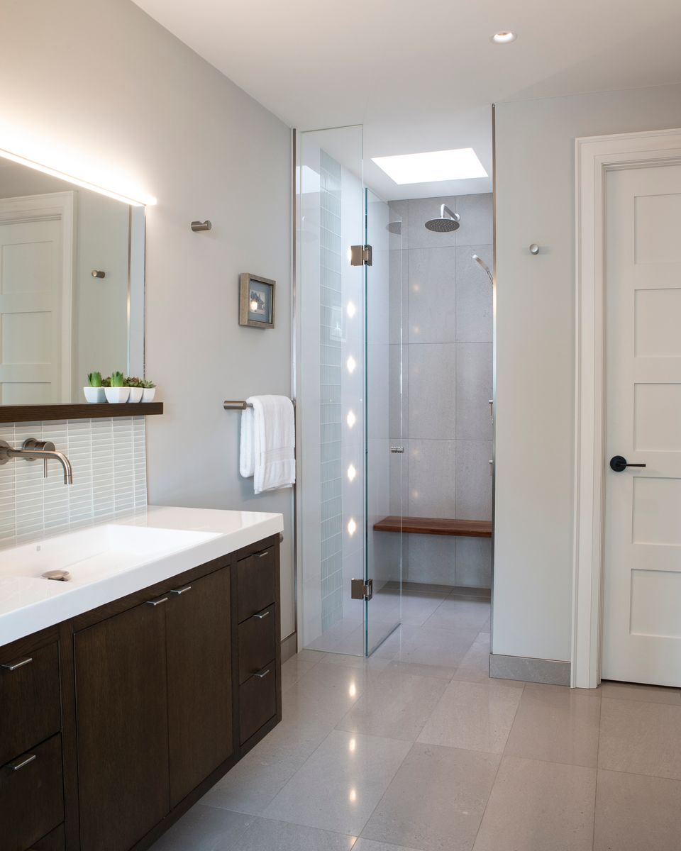 bright luxury bathroom renovation in toronto with walk in shower and floating faucet