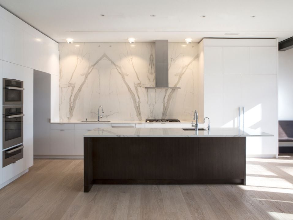 Luxury kitchen in custom home with slab backsplash and white custom cabinets
