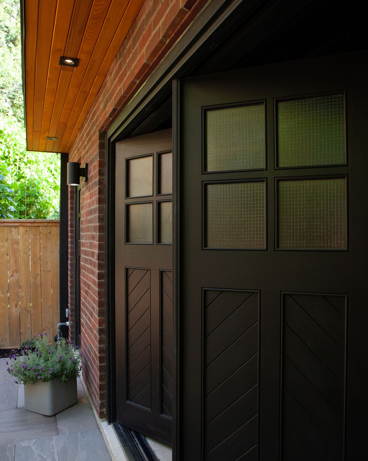 Exterior of paneled chevron door with bi fold door