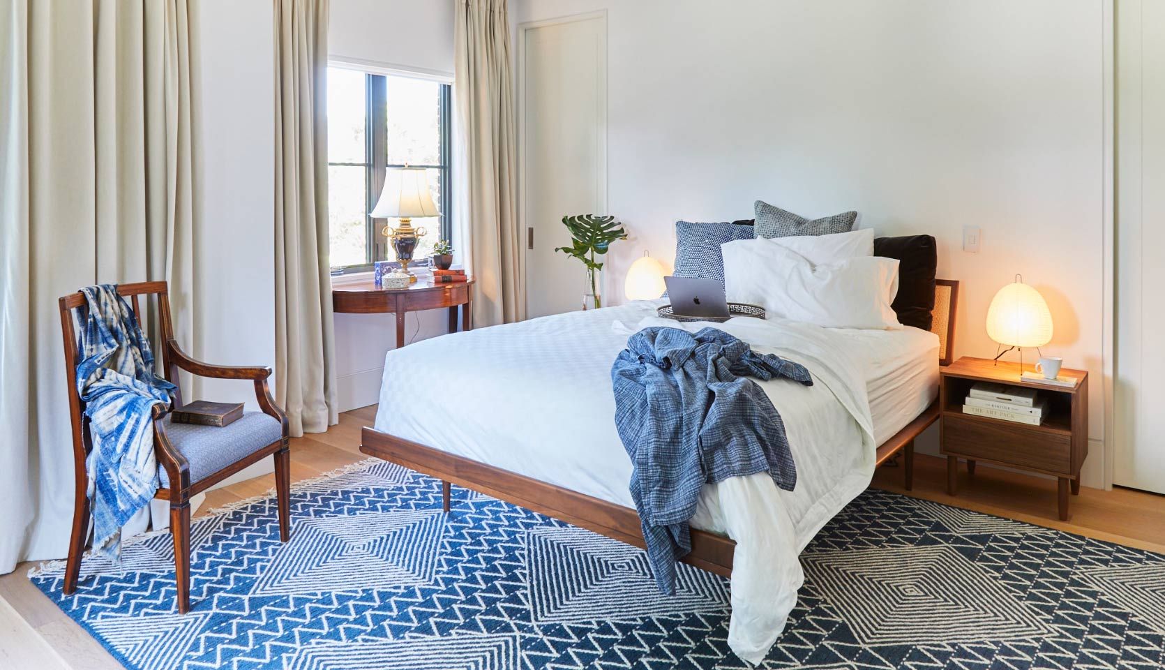 Bedroom in custom home with beige curtains and white walls with wood furniture