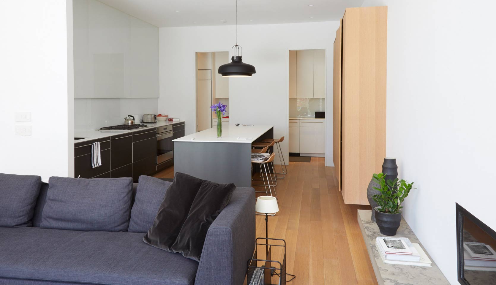 View of kitchen from great room with modern hanging light fixture above island with seating