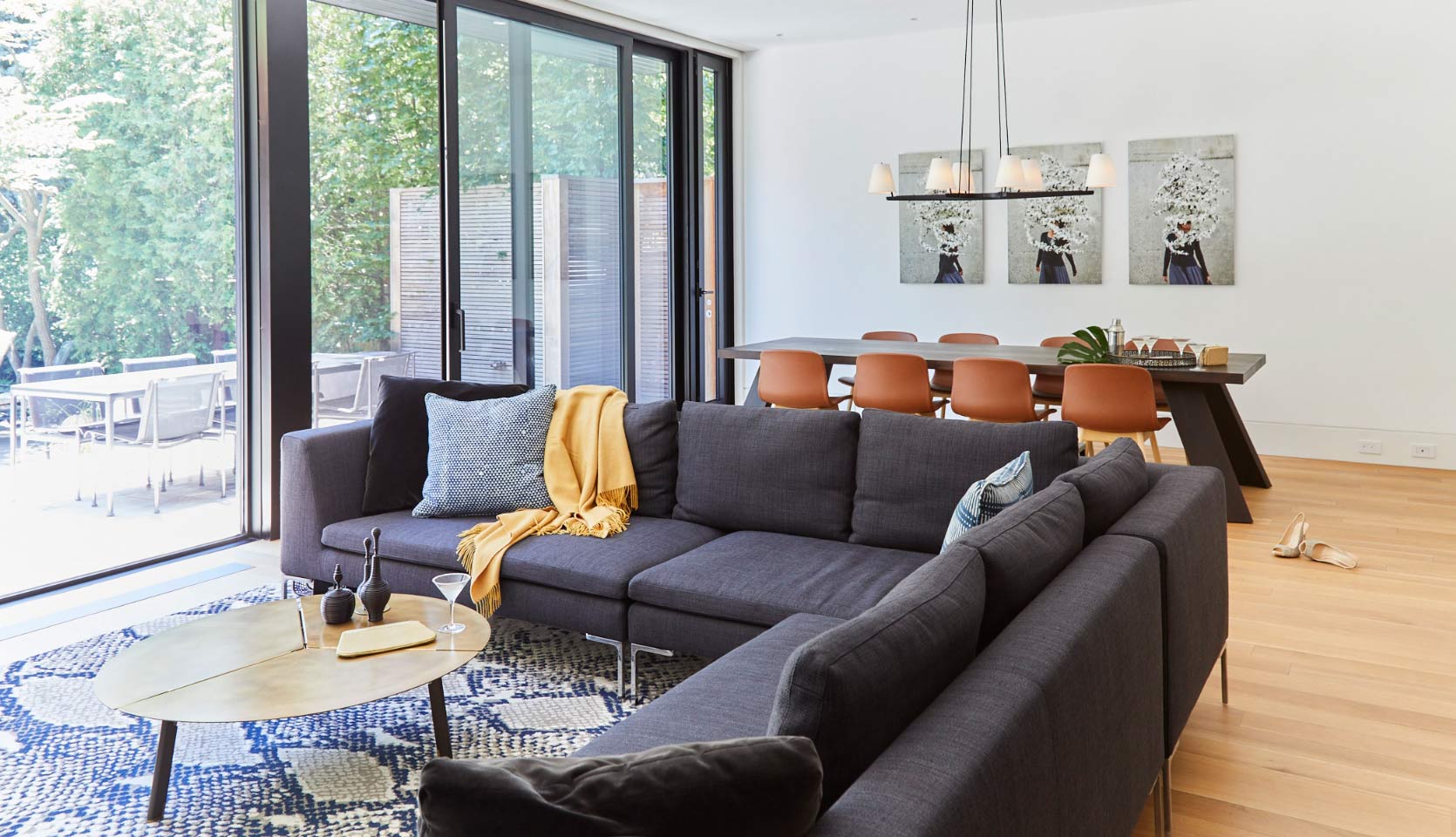 Great room area with pendant lighting above dining table and full-width windows with sliding glass door to yard