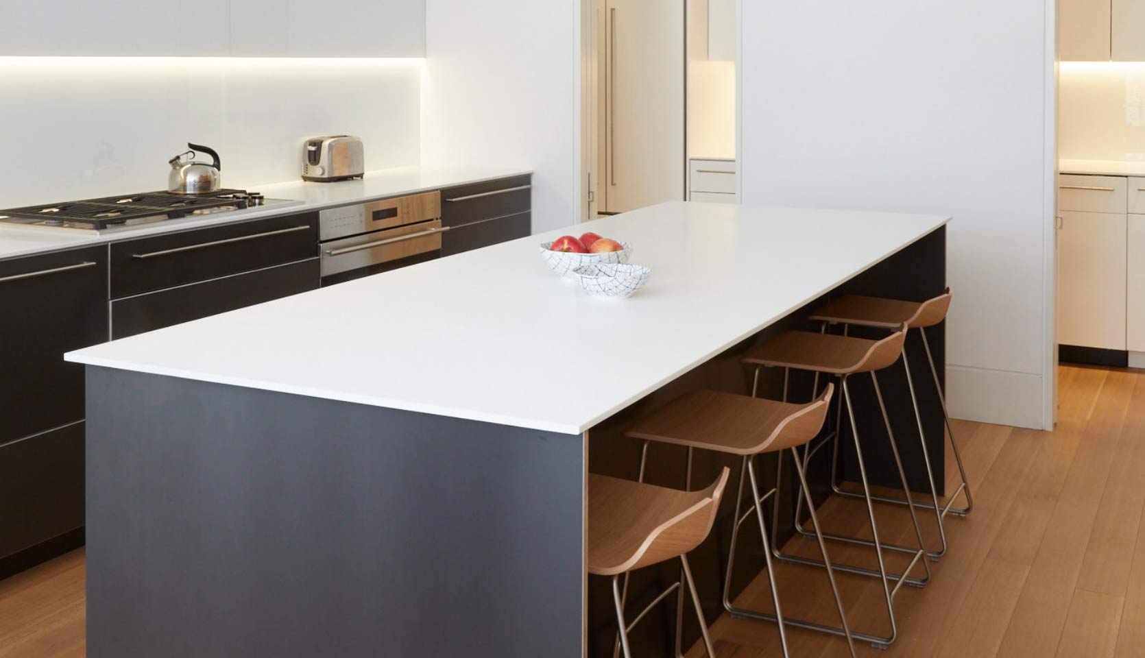 Kitchen island with white countertop and four barstools beneath