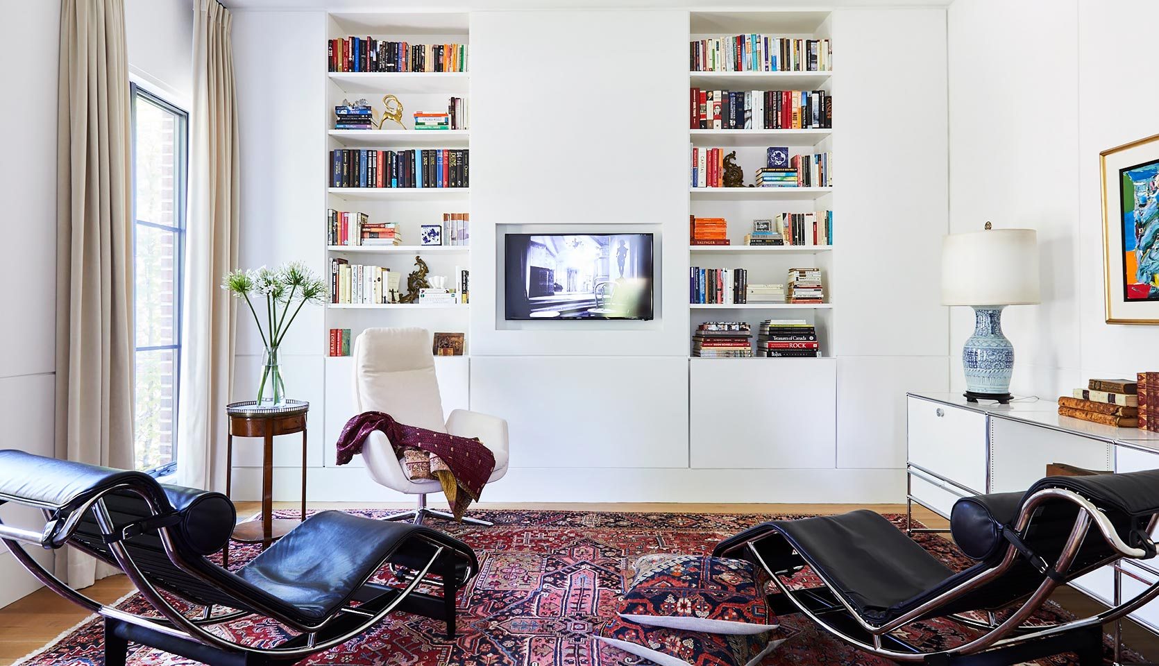 Modern custom home study with built-in white shelving and TV in middle