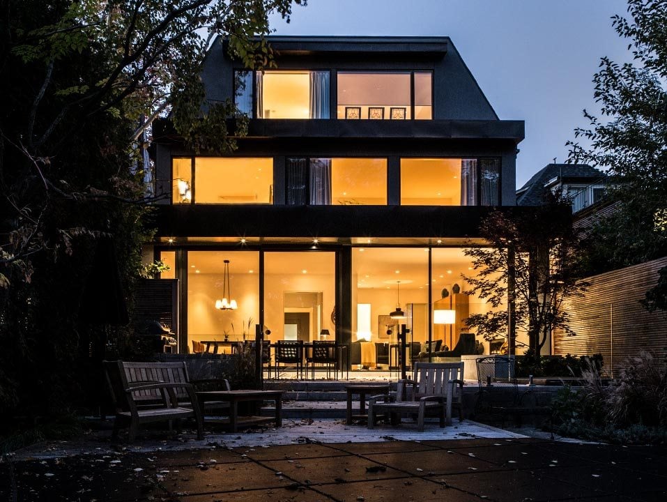 modern contemporary exterior home at dusk with lots of windows and indoor lights on